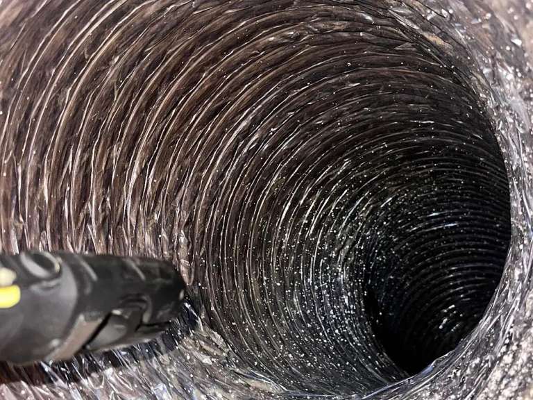 The inside of a flexible duct after cleaning, the brush head at the left