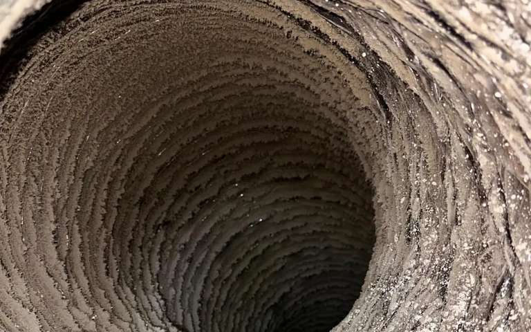 The inside of a flexible duct thickly caked with lint