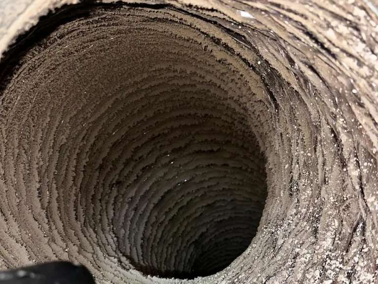 The inside of a flexible duct thickly caked with lint