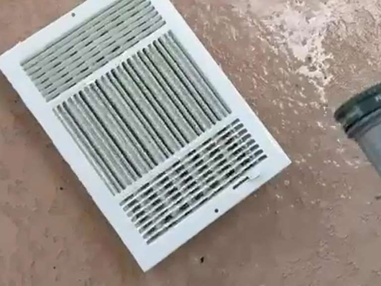 A white air register grille removed and lying on the floor
