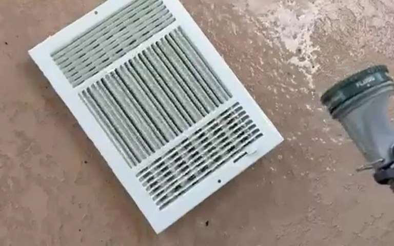 A white air register grille removed and lying on the floor