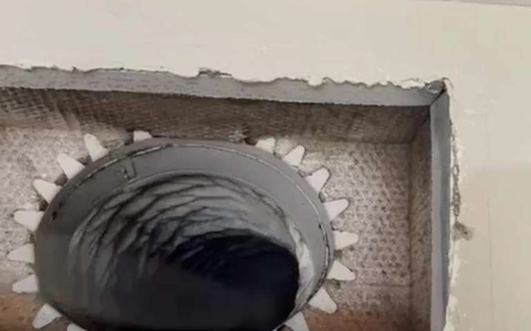 An opened register boot with a brush head entering the duct