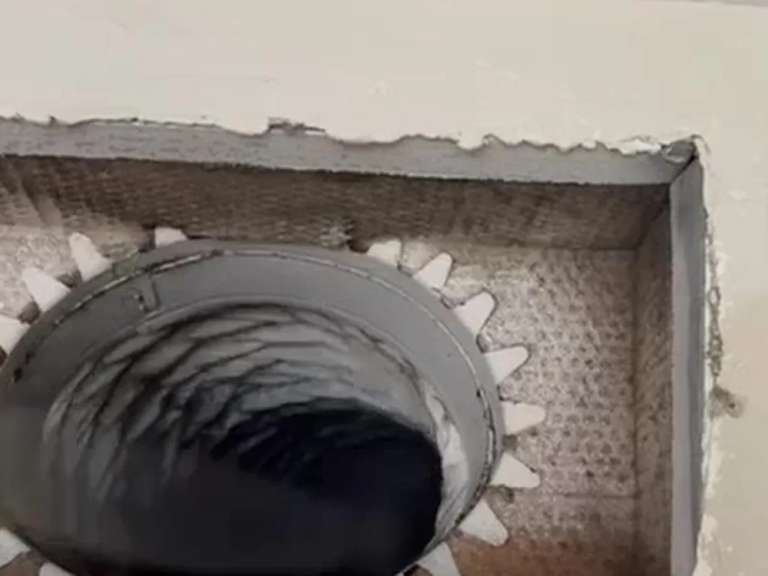 An opened register boot with a brush head entering the duct